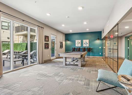 A spacious living room with a grey carpet and a blue chair.