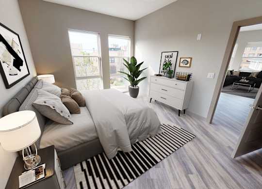A bedroom with a bed, nightstand, and a plant at Crossroads 389 Apartments, Hackensack, NJ
