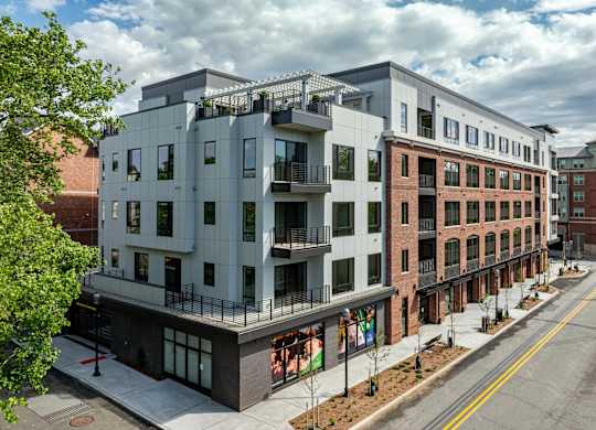A modern building with a balcony is situated on a street.