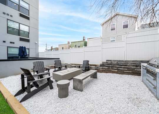A patio with a table and chairs is surrounded by a white fence.