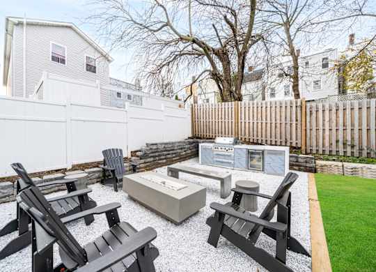 A backyard with a white fence and black furniture.