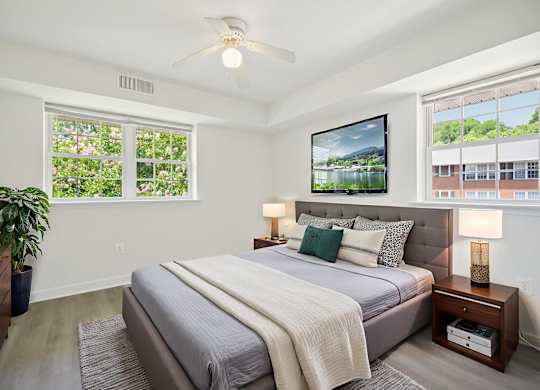 A bedroom with a bed, a ceiling fan, and a large window.