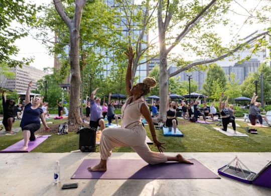 A woman in a white dress is doing yoga in a park.