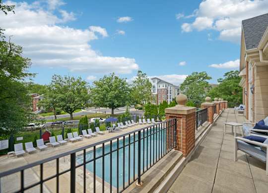 A pool surrounded by a fence and chairs.