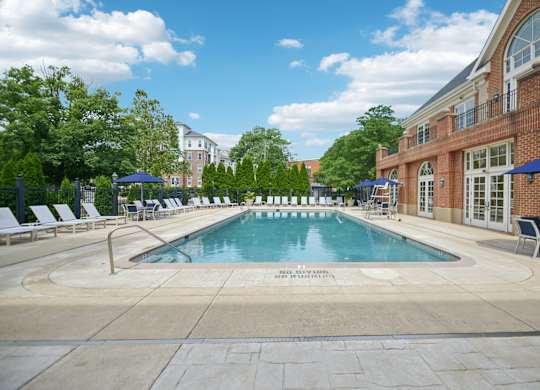 A large outdoor swimming pool surrounded by lounge chairs and umbrellas.