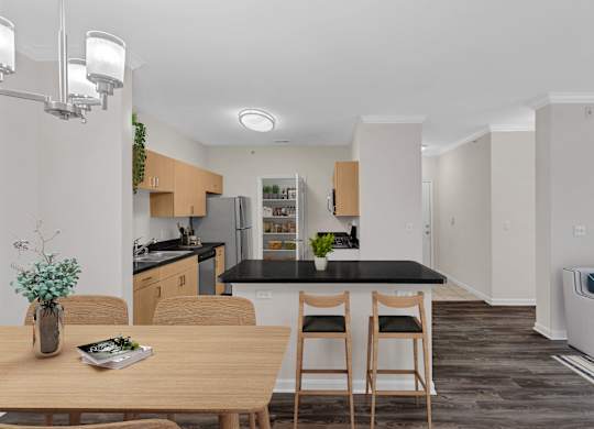 A kitchen with a black countertop and wooden chairs.