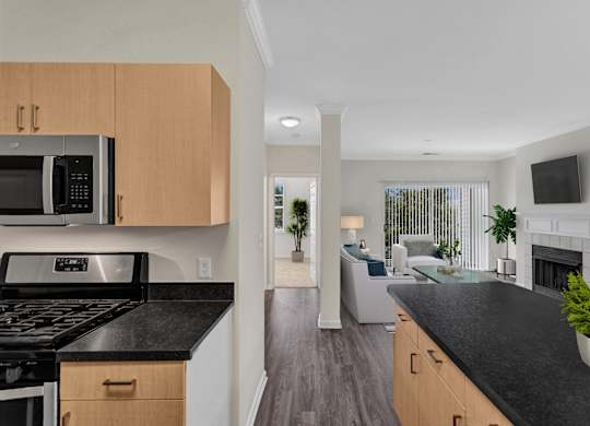 A modern kitchen with black countertops and wooden cabinets.