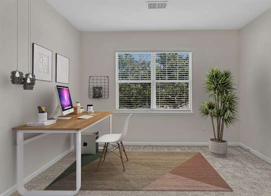 A room with a desk, chair, and a plant.