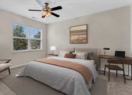 A bedroom with a bed, desk, chair, and a ceiling fan.