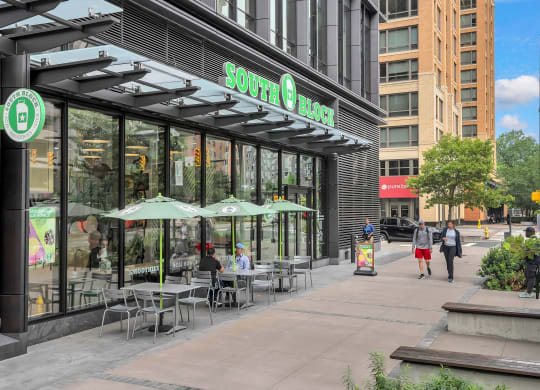 people walking down a sidewalk in front of a coffee shop