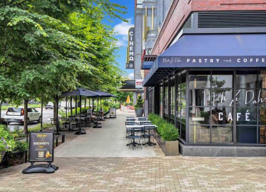 a sidewalk outside of a coffee shop with tables and chairs