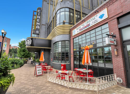 a sidewalk outside of a restaurant with red tables and chairs