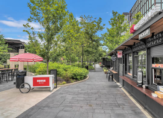 a sidewalk with shops and trees on the side of a street