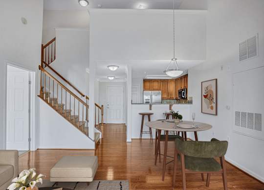 A living room with a staircase and a dining table.
