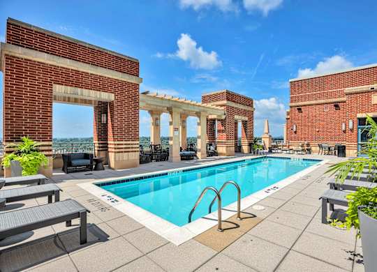 A pool surrounded by a brick wall with a white archway.