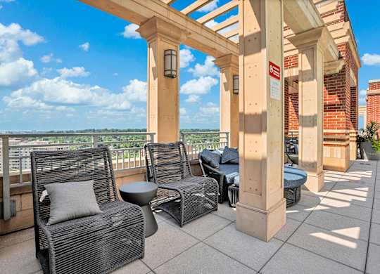 A patio with a wicker chair and a table with a cushion on it.