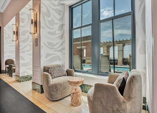 Two chairs and a table are in a room with a large window.