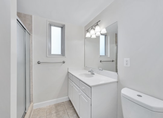 a bathroom with a white sink and toilet next to a shower with a glass door