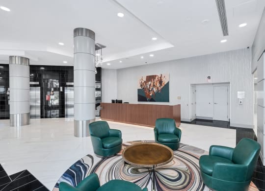 a lobby with green chairs and a round coffee table