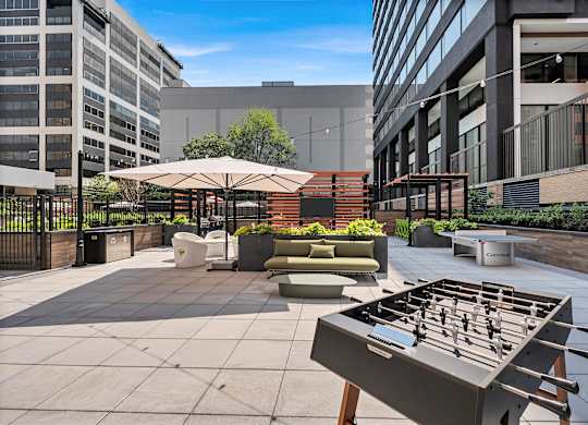 A foosball table is in the middle of a courtyard with a building in the background.