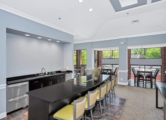 a kitchen with a long black counter and yellow chairs