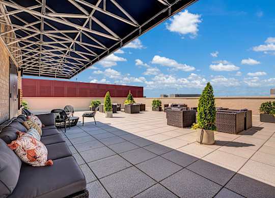A patio with a couch and a table with a potted plant on it.