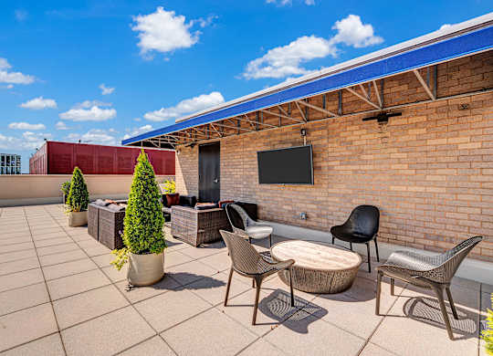 A patio with a table, chairs, and a TV mounted on a brick wall.