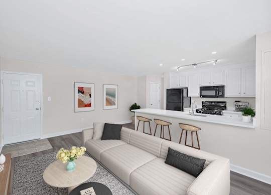 A living room with a couch, coffee table, and kitchen area in the background.