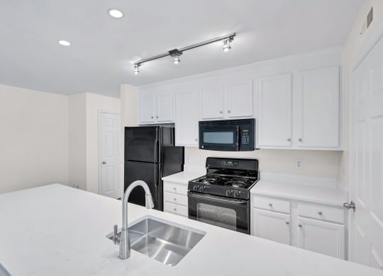 a kitchen with white cabinets and black appliances