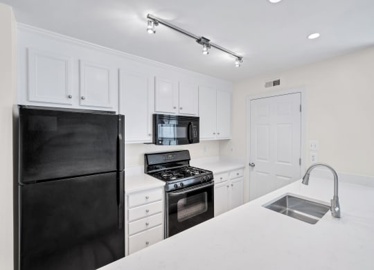 a kitchen with white cabinets and black appliances