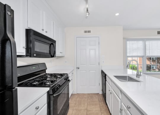 a kitchen with white cabinets and black appliances