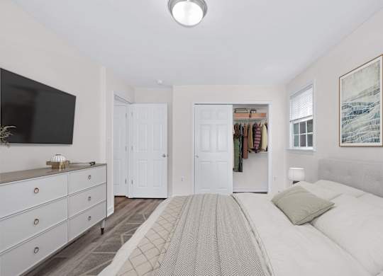 A bedroom with a large bed and a television on the wall.