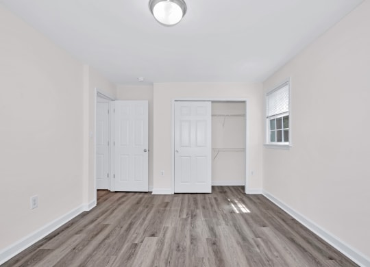 a bedroom with hardwood floors and white walls