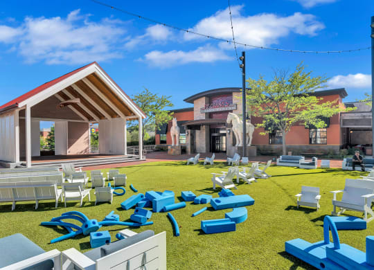 a yard with chairs and tables and a building in the background