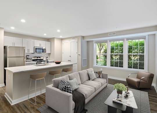 A modern living room with a kitchen area in the background.