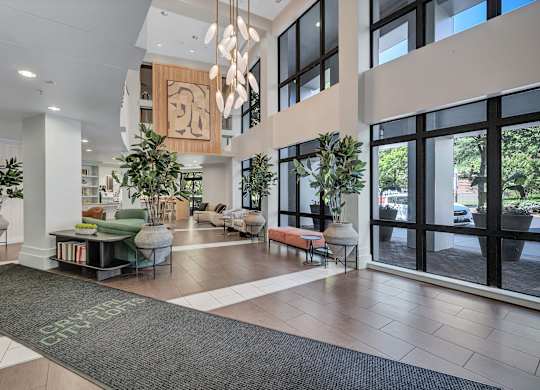 A modern lobby with a green rug on the floor and a large glass door.