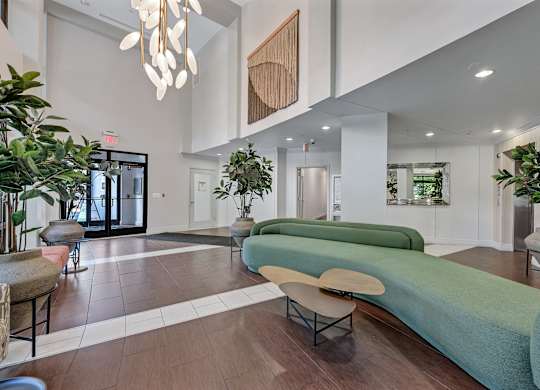A modern living room with a long green couch and a wooden beam on the wall.