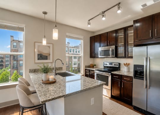 A modern kitchen with a granite countertop and stainless steel appliances.