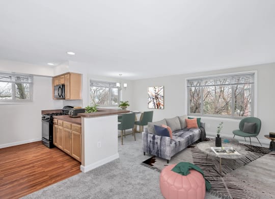 a living room with a couch a table and a chair and a kitchen with a stove and