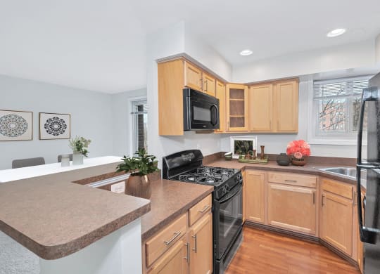 a kitchen with maple cabinets and black appliances