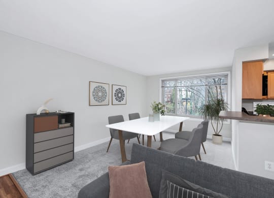 a dining area with a table and chairs and a kitchen in the background