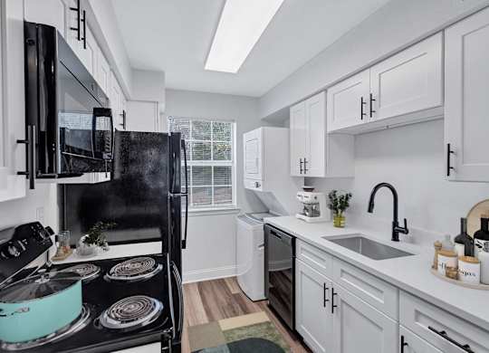 A modern kitchen with a black stove top and white cabinets.