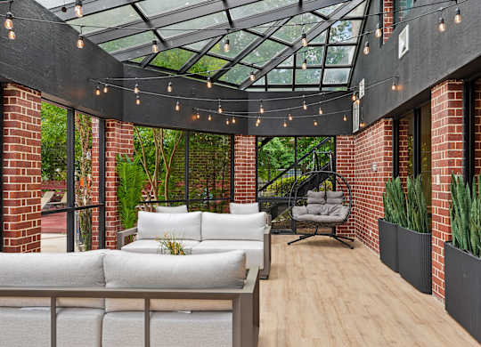 A patio with a white couch and a glass roof.