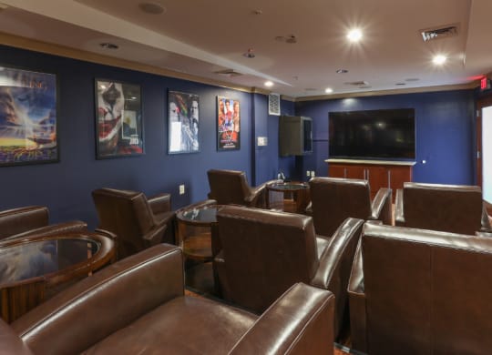 a cinema room with leather chairs and a flat screen tv