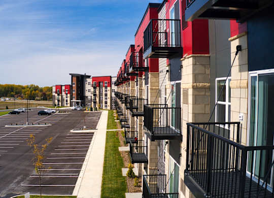 A parking lot in front of a row of apartment buildings.