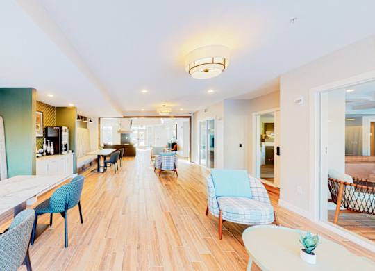 A long white table with blue chairs is in the middle of a room.