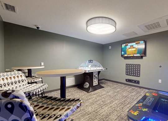 A room with a table, chairs, and a television mounted on the wall.