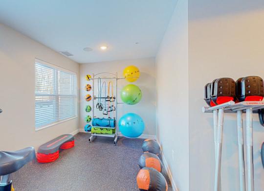 A room with a treadmill, exercise balls, and resistance bands.