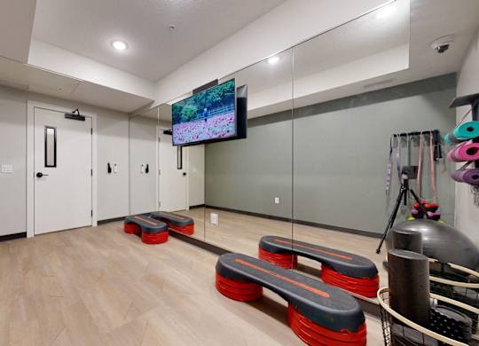 A room with a wooden floor and a television mounted on the wall.