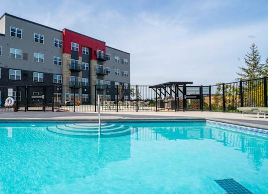 A swimming pool in front of a multi-story apartment building.
